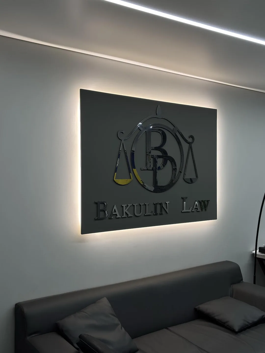 Приймальня: підсвічений логотип Bakulin Law над шкіряним диваном